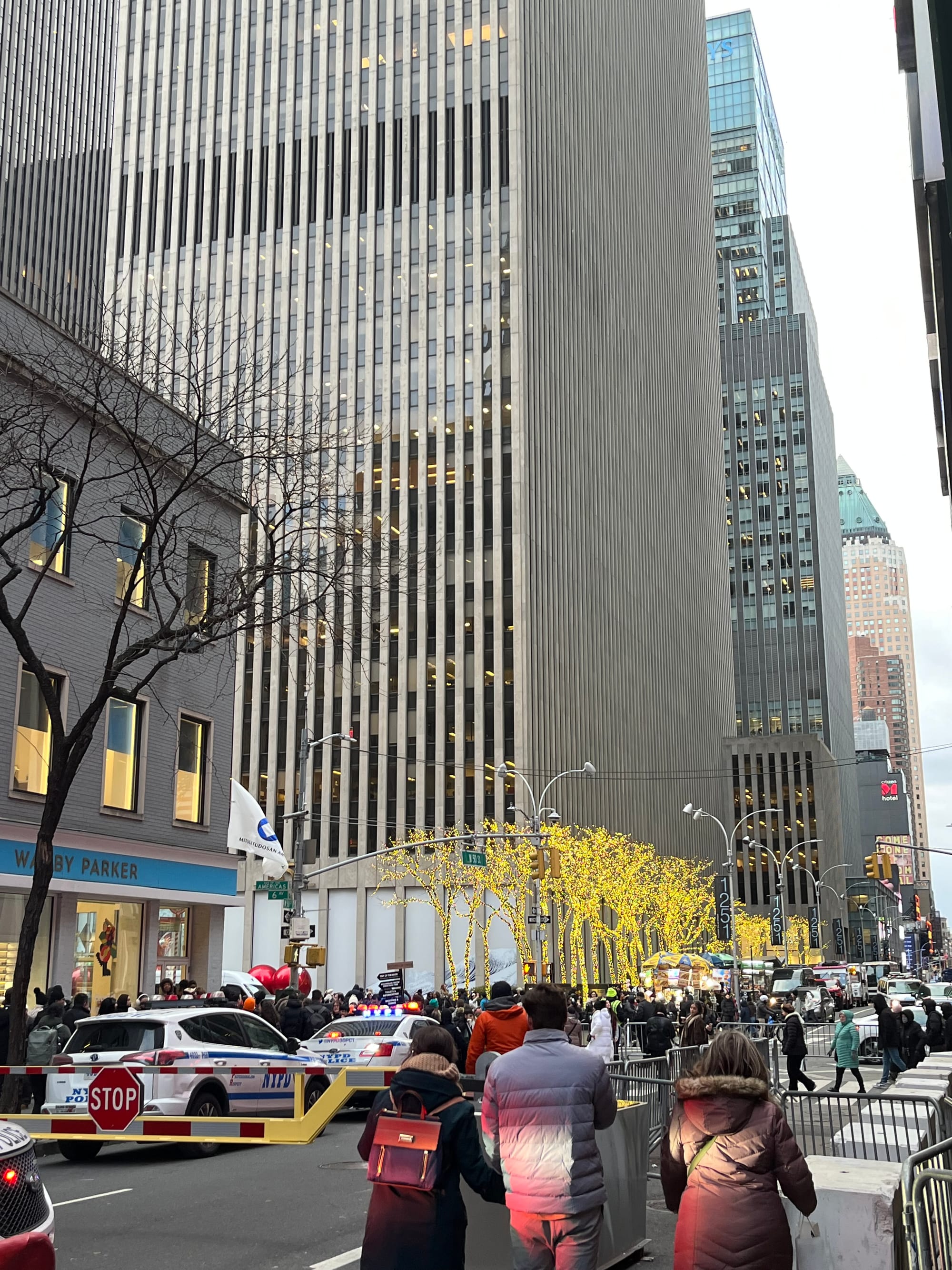 Police cars and fences surround a long line of people.