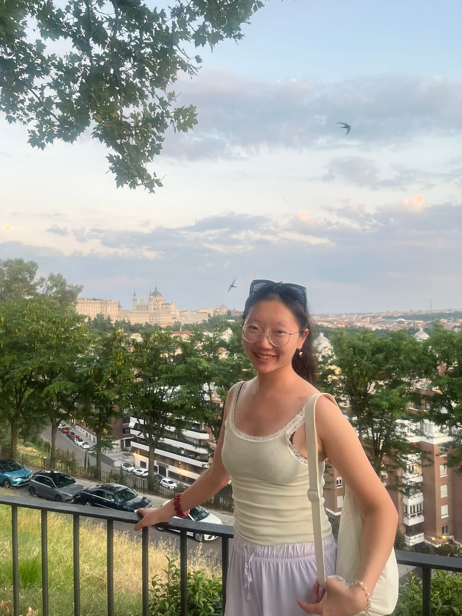 girl smiling serenely at camera with cathedral in background and birds in sky