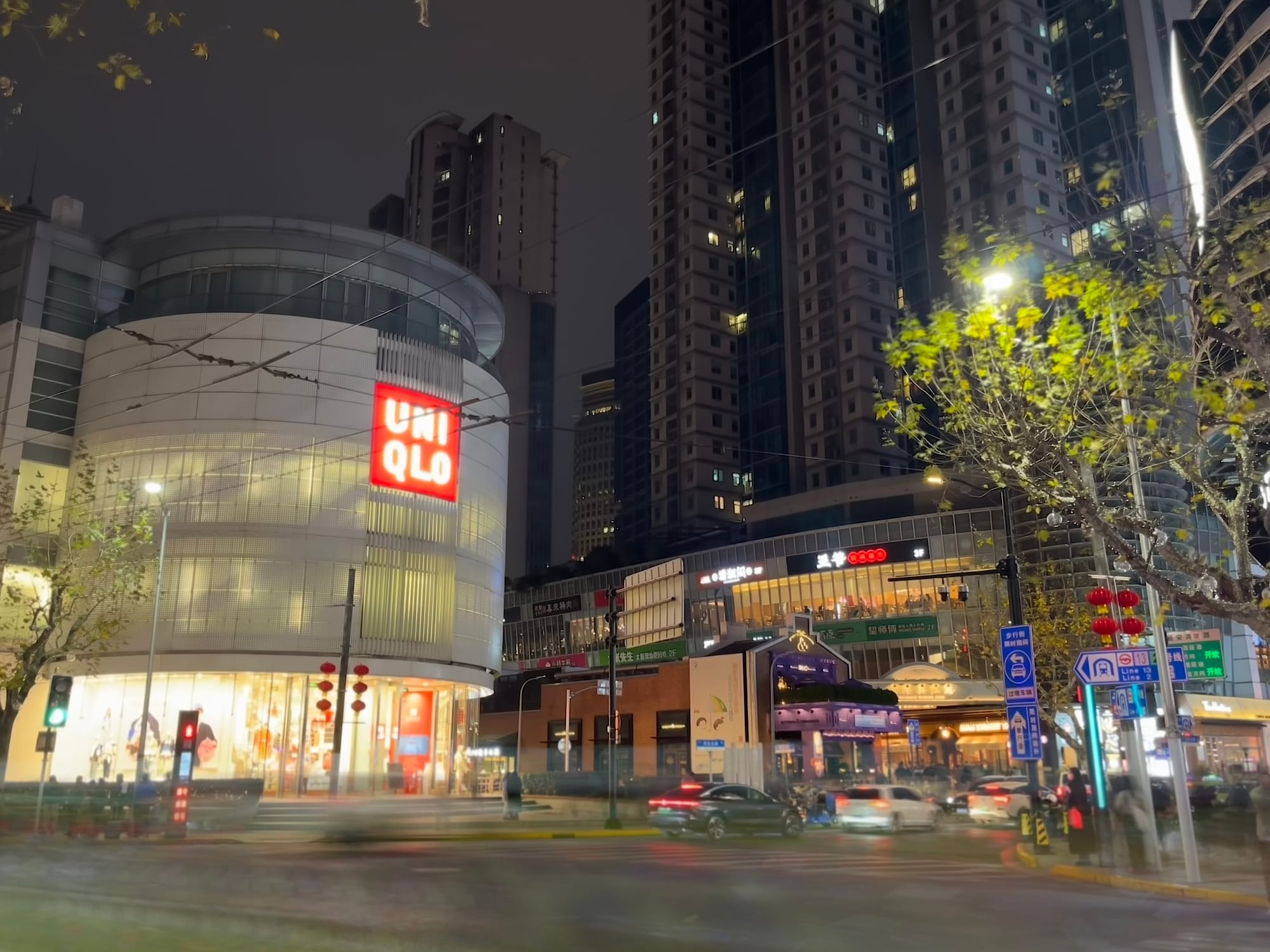 cars speeding by an urban mall featuring "Uniqlo"