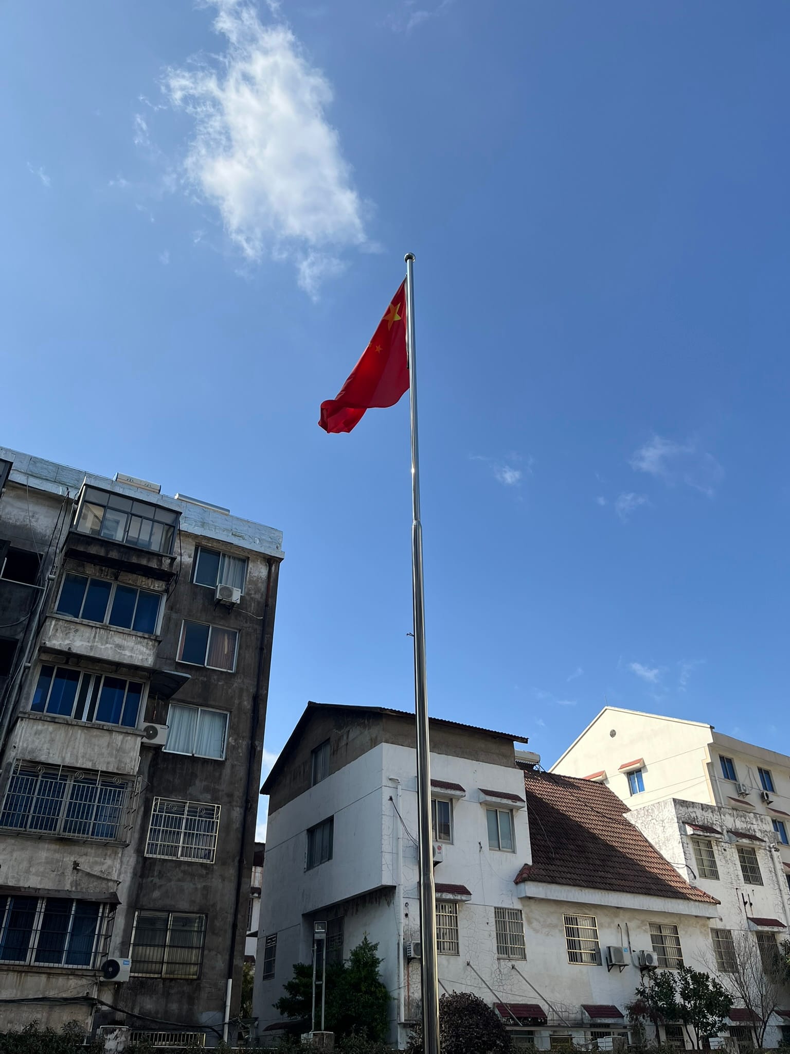 red Chinese flag blowing in the wind in front of dilapidated apartments
