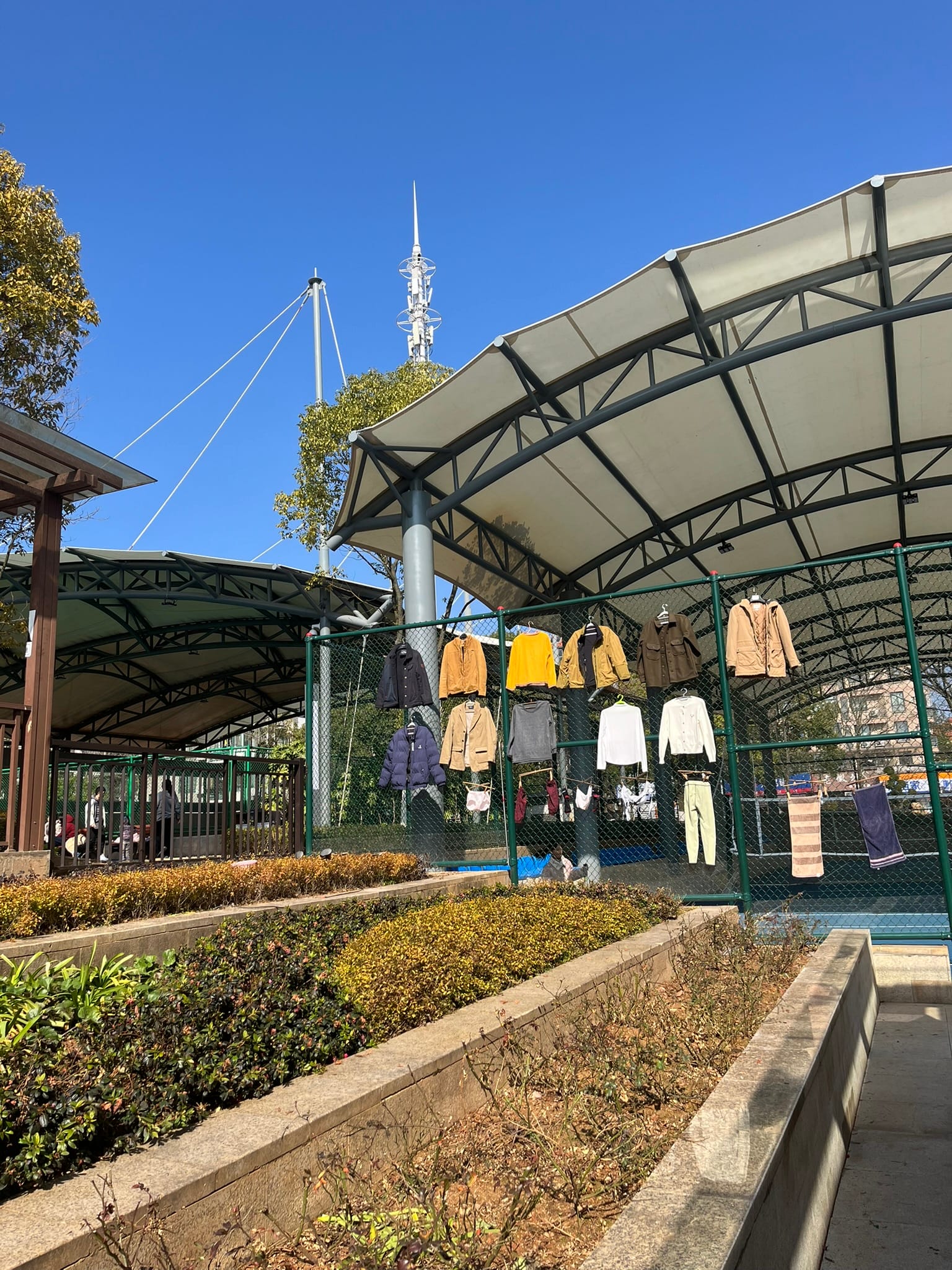 laundry hung on a tennis court fence drying in the sun