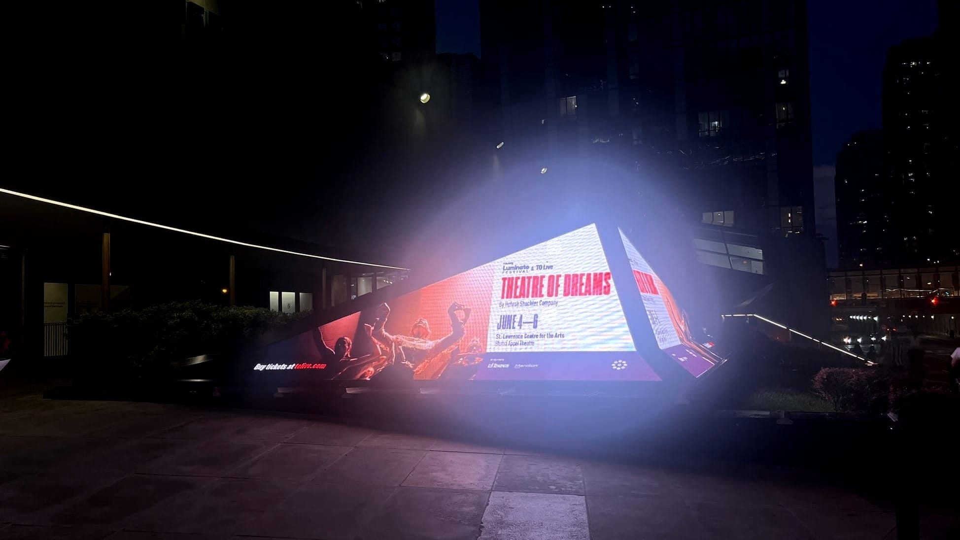 triangular LED sign marketing a dance show called "Theatre of Dreams"